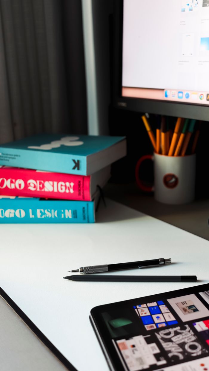 Modern workspace featuring design books, tablet, pen, and computer monitor, ideal for creative professionals.
