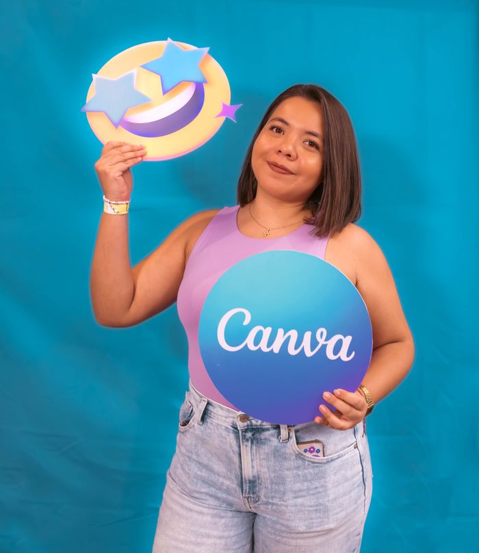 Portrait of a young woman holding Canva logo and emoji on a blue background.
