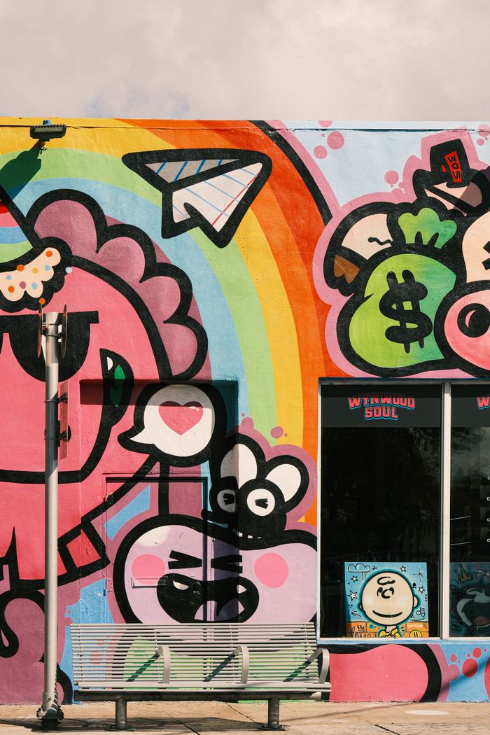 about-us Colorful street art mural featuring playful cartoon characters and a rainbow in an urban setting.